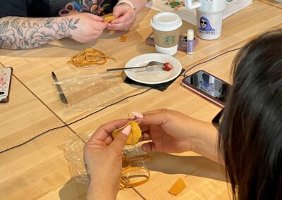 Two people sewing a pouch during an arts-based activity